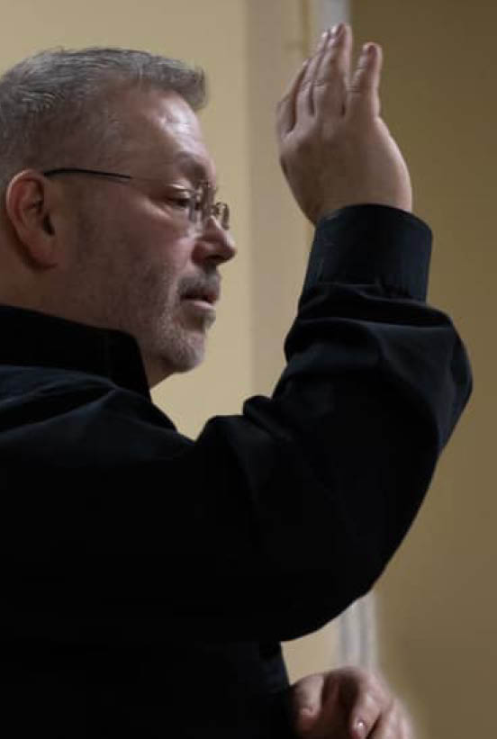 John Bradley raising hand directing choir