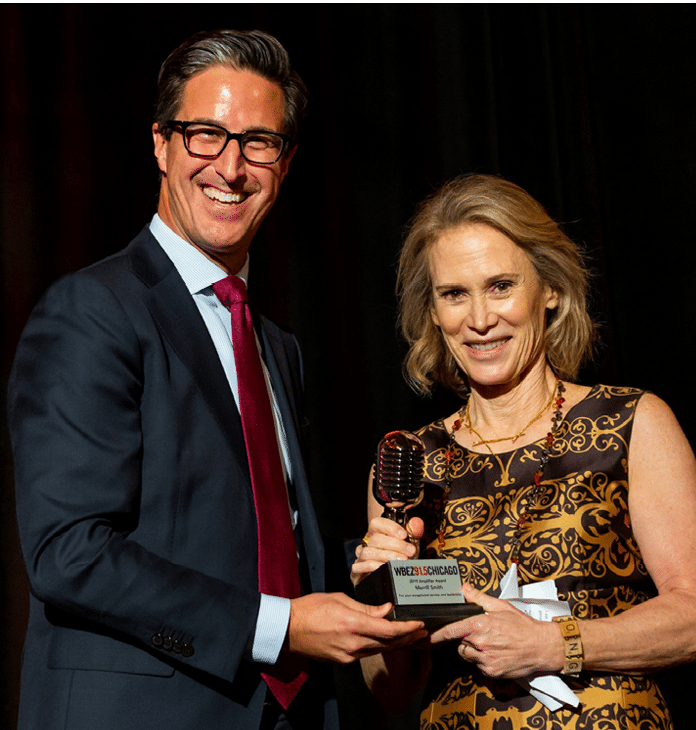 Merrill standing holding award with a man in a suit