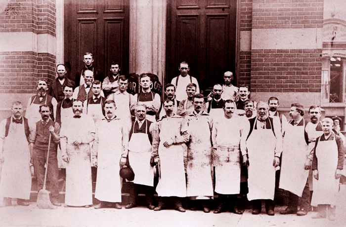 Historical photo of a group of employees standing out front of building