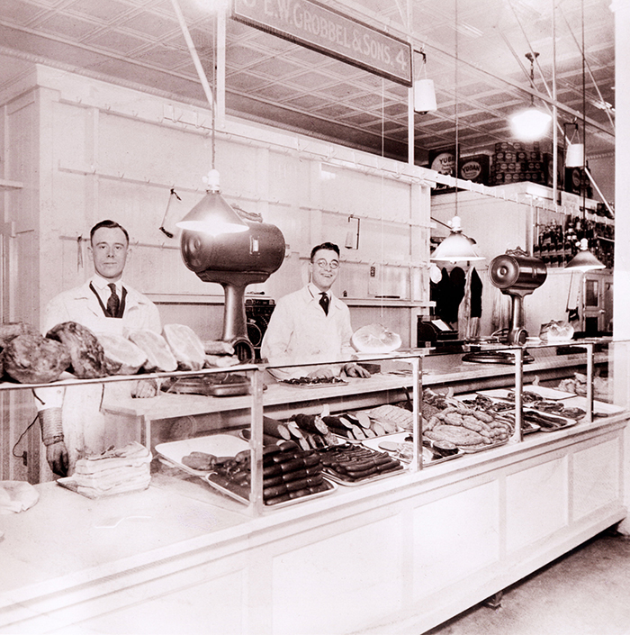 Historical photo of two butches behind meat counter