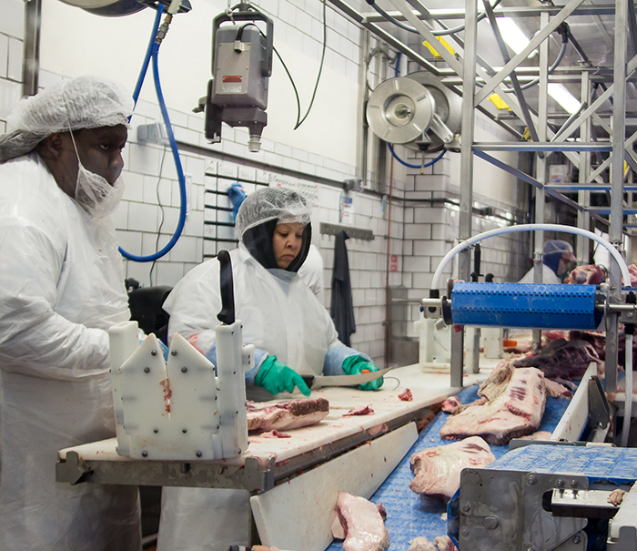 Workers trimming meat in the plant