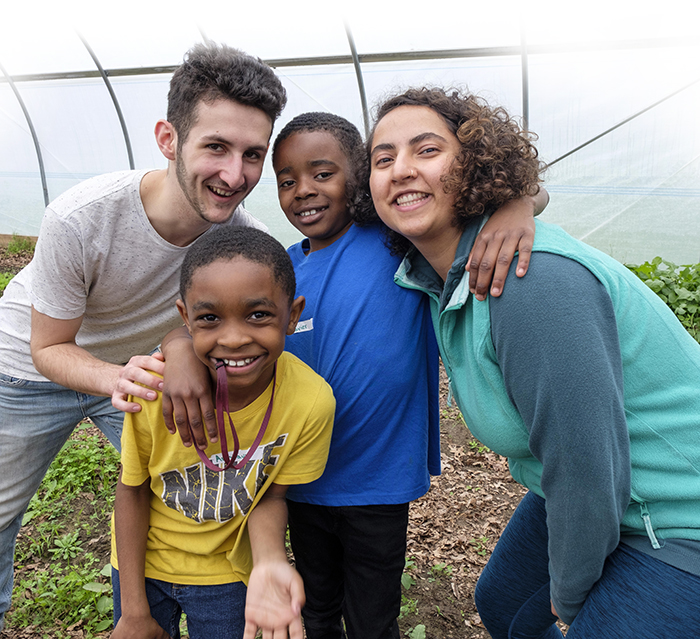 two Kalamazoo College students posing with two Woodward elementary school students in the Hoop House