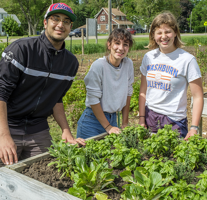 Three students standing over a planter box