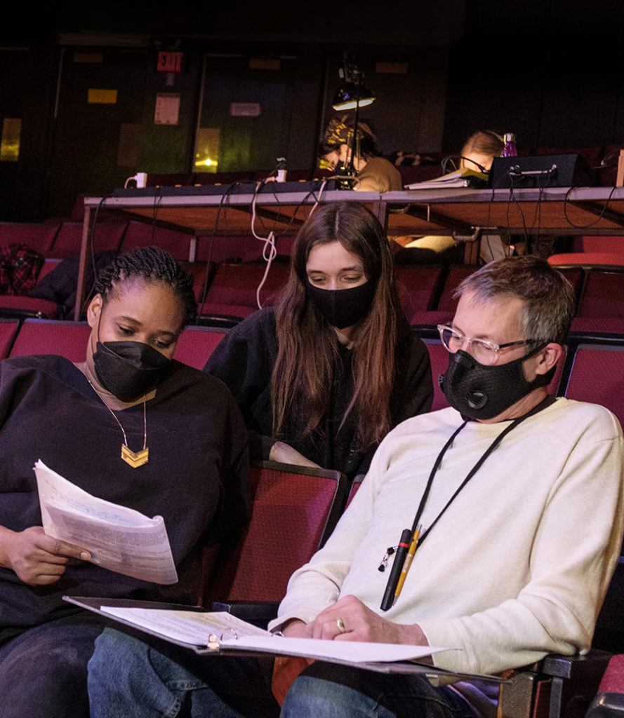 Angela Mammel, Dee Dee Batteast and Lanny Potts looking at a script sitting in theatre seats