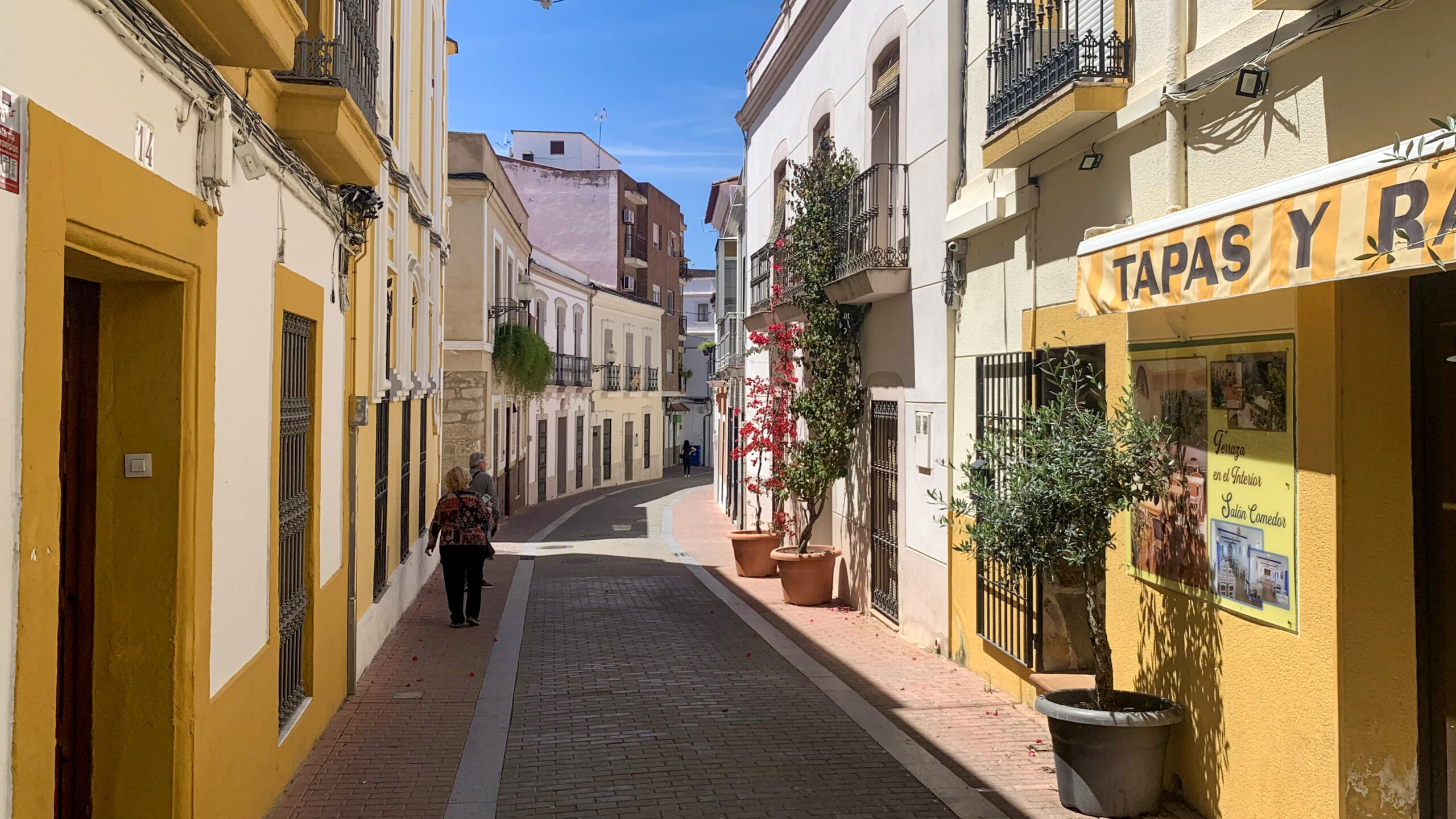 A vibrant street scene in Merida, Spain, showcasing colorful buildings and a lively atmosphere.