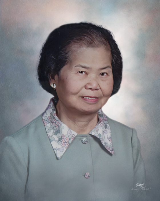 Margaret (Wong) Hwang '55, an older woman with dark hair, smiling in a light green dress with a white collar featuring a floral and butterfly pattern, against a soft, blurred background.