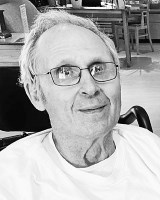 Barent 'Peter' Landstreet '64, an older man with white hair and glasses, smiling in a black-and-white photo while wearing a white shirt, seated in a room with a table, chairs, and various items in the background.