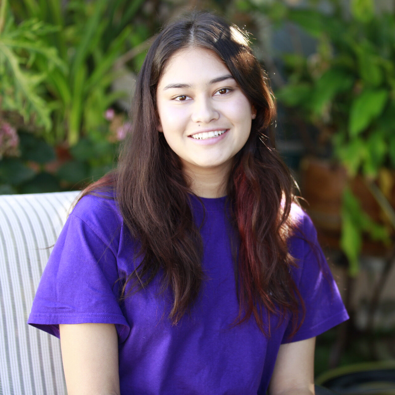 Emily Avalos sitting in a purple shirt, smiling