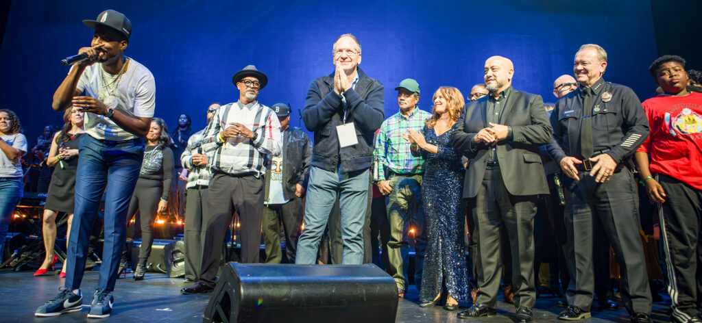 Filmmakers gather on stage at the Peacock Theatre with Michael Soenen at center with hands pressed together, smiling.