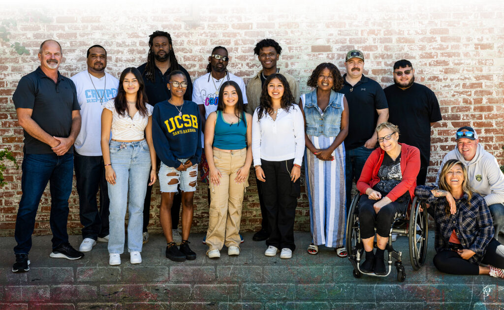 Watts Filmmakers line up for a photo against a brick wall. 